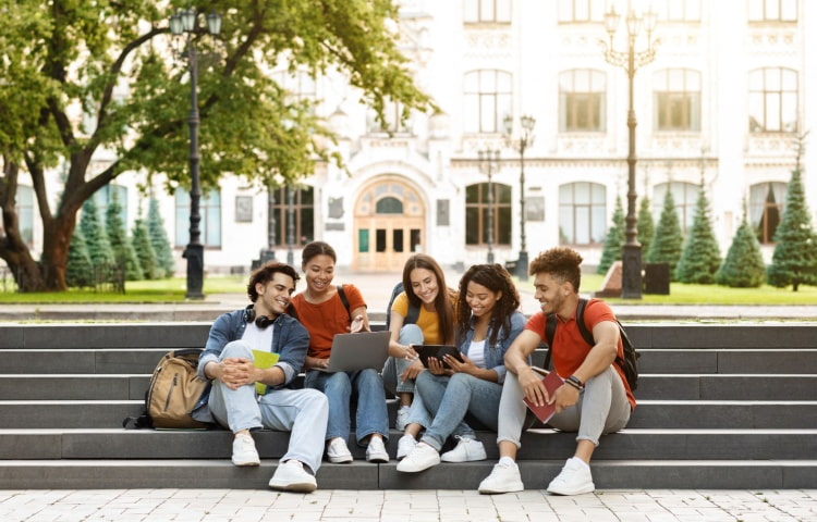 A group of high school students sit together on outdoor steps